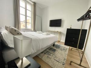 una camera bianca con letto e televisore di StandingHouse Marmande Centre a Marmande