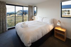 a bedroom with a large bed with a large window at Loudon Lodge - Lake Tekapo in Lake Tekapo