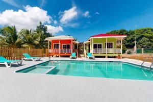 a house with a swimming pool and two houses at Came at Hummingbird Estate Gold Standard Certified in Dangriga