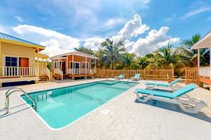 a swimming pool with two chairs and a house at Came at Hummingbird Estate Gold Standard Certified in Dangriga