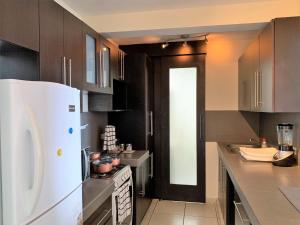 a kitchen with a white refrigerator and a black door at Luxury Modrn Apartment, w/amazing view, 3BR,Escalon,Exclus,Secur in San Salvador