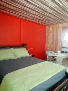 um quarto com uma cama e uma parede vermelha em Hostel Osa Tucan Drake em Drake