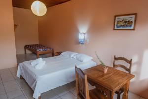 a bedroom with a bed and a table and a chair at Alecrim Pousada in Praia do Rosa