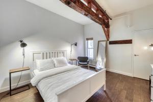 a white bedroom with a bed and a chair at The Mill #210 in Ludlow