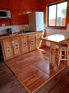 a kitchen with a table and a refrigerator at Cabañas Trabun-Leufu in La Unión