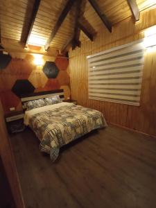 1 dormitorio con 1 cama en una habitación de madera en Cabañas Trabun-Leufu, en La Unión