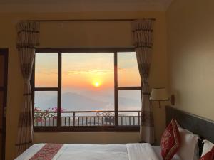een slaapkamer met een raam met uitzicht op de zonsondergang bij Superview Lodge Sarangkot in Pokhara
