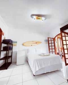 a bedroom with a bed and a surfboard on the wall at Pousada Praia do Tombo in Guarujá