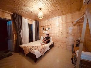 un hombre sentado en una cama en un dormitorio en Khách sạn Anh Đào en Tam Ðảo