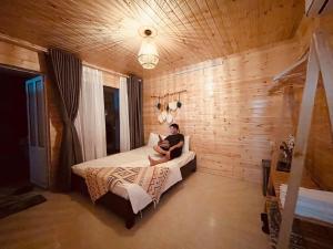 a man sitting on a bed in a bedroom at Khách sạn Anh Đào in Tam Ðảo