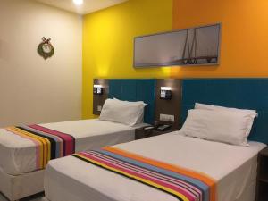 Hotel White Fields Hitec City, Hyderabad في حيدر أباد: سريرين في غرفة مع تلفزيون على الحائط