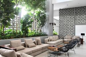 a lobby with a couch and chairs and plants at Bell Suites @ Sepang by Moka in Sepang