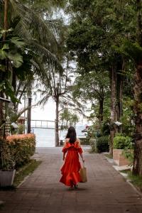 a girl in a red dress walking down a sidewalk at Aonang Buri Resort- SHA Extra Plus in Ao Nang Beach