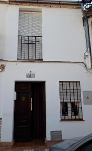 een wit gebouw met een bruine deur en ramen bij Aurorero Antonio in Arriate
