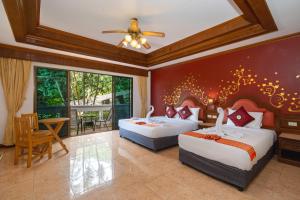 a bedroom with two beds and a table and chairs at Memory Karon Resort in Karon Beach