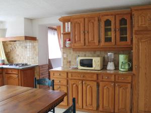 eine Küche mit Holzschränken und einem Tisch mit Mikrowelle in der Unterkunft Gîte La Saucelle, 4 pièces, 6 personnes - FR-1-581-57 