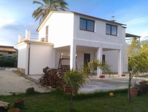 a white house with palm trees in front of it at 1st floor apartment in villa Falari near the in Avola