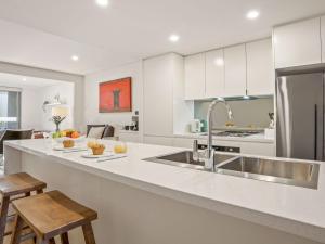 a kitchen with a sink and a counter with stools at Riptide on Surf Beach in Kiama