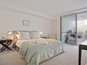 a white bedroom with a bed and a large window at Riptide on Surf Beach in Kiama