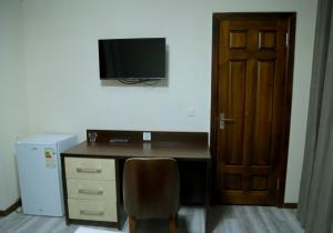 a desk with a chair and a television on a wall at Grand Ark Bukhara in Bukhara