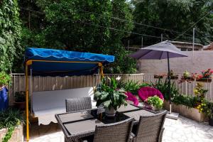 eine Terrasse mit einem Tisch, einem Sonnenschirm und Stühlen in der Unterkunft Rooms Edna in Dubrovnik