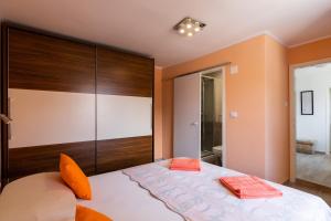 ein Schlafzimmer mit einem großen Bett mit orangefarbenen Kissen darauf in der Unterkunft Rooms Edna in Dubrovnik