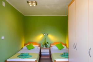 2 Betten in einem Zimmer mit grünen Wänden in der Unterkunft Rooms Edna in Dubrovnik