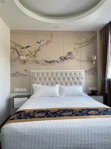 a bedroom with a large white bed with a wall at KYRIAD ROUEN SUD - Sotteville les Rouen in Rouen