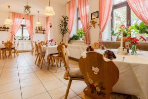 a restaurant with tables and chairs and pink curtains at Hotel Carola in Olbernhau