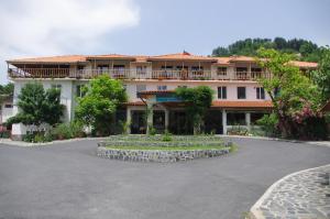 a large white building with a courtyard in front of it at Edi Hotel in Zlatograd