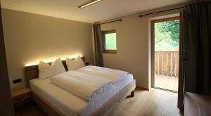 1 dormitorio con 1 cama blanca y ventana en Bergchalet Prantach en San Martino