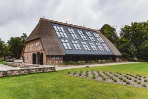 a large building with a thatched roof at Gut Damp Ferien Lofts in Damp