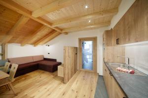 - une cuisine avec un canapé dans une chambre dotée de plafonds en bois dans l'établissement Schartnerhof Ferienwohnung Salbei, à Vols am Schlern