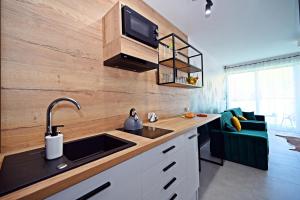 una cucina con lavandino e una TV a parete di Szczyrk Apartament Natura z Sauną nad Żylicą a Szczyrk