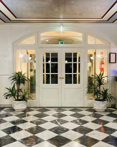 a lobby with a white door and two potted plants at Hotel Master in Albignasego