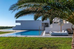 a villa with a pool and a palm tree at Sovereign Beach Hotel in Kardamaina