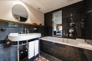 un bagno con un lavandino, una vasca e uno specchio di La Cordée des Alpes SUP a Verbier