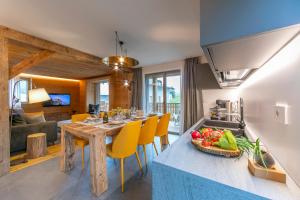 een keuken en een woonkamer met een houten tafel en gele stoelen bij Besseghini Apartments in Livigno