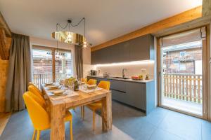 een keuken en eetkamer met een houten tafel en gele stoelen bij Besseghini Apartments in Livigno