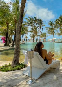 Billionaire Resort & Retreat Malindi في ماليندي: امرأة تجلس على كرسي على الشاطئ