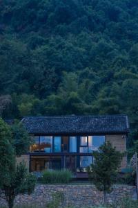 une maison en pierre avec des fenêtres en verre sur une colline dans l'établissement Yangshuo Hillside Homestay, à Yangshuo