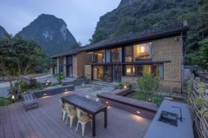 une maison avec une table et des chaises sur une terrasse dans l'établissement Yangshuo Hillside Homestay, à Yangshuo