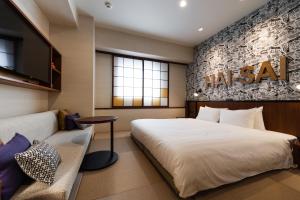 a bedroom with a large bed and a couch at PROSTYLE RYOKAN Naha Kenchou Mae in Naha