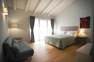 ein Schlafzimmer mit einem Bett, einem Sofa und einem Fenster in der Unterkunft Il Fienile in Fagagna