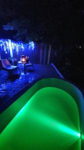 una piscina verde iluminada por la noche con una mesa en VIP Yellow dream house Sodyba Geras en Anykščiai