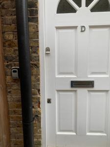 een witte deur naast een stenen muur bij Cozy 1 Bedroom Basement Flat in Londen