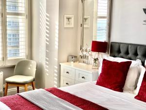 um quarto com uma cama com almofadas vermelhas e uma cadeira em A Room With A View em Brighton & Hove
