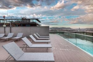 a deck with white chairs and a pool on a building at Great apartment with view and heated rooftop Pool in Vienna