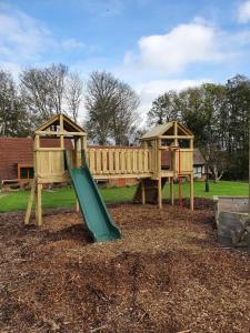 un parque infantil con un tobogán verde y dos cenadores en Glyndley Manor Cottages en Polegate