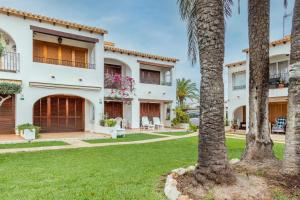 a house with palm trees in the yard at Spacious Ground Floor Apartment in Denia